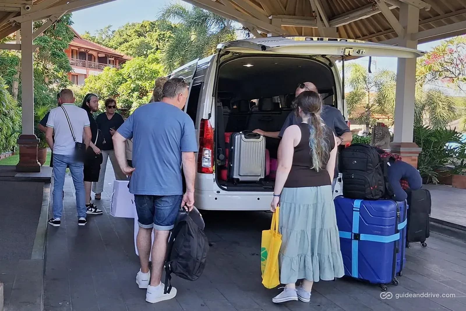 Guests loading suitcases into a minibus at a hotel entrance