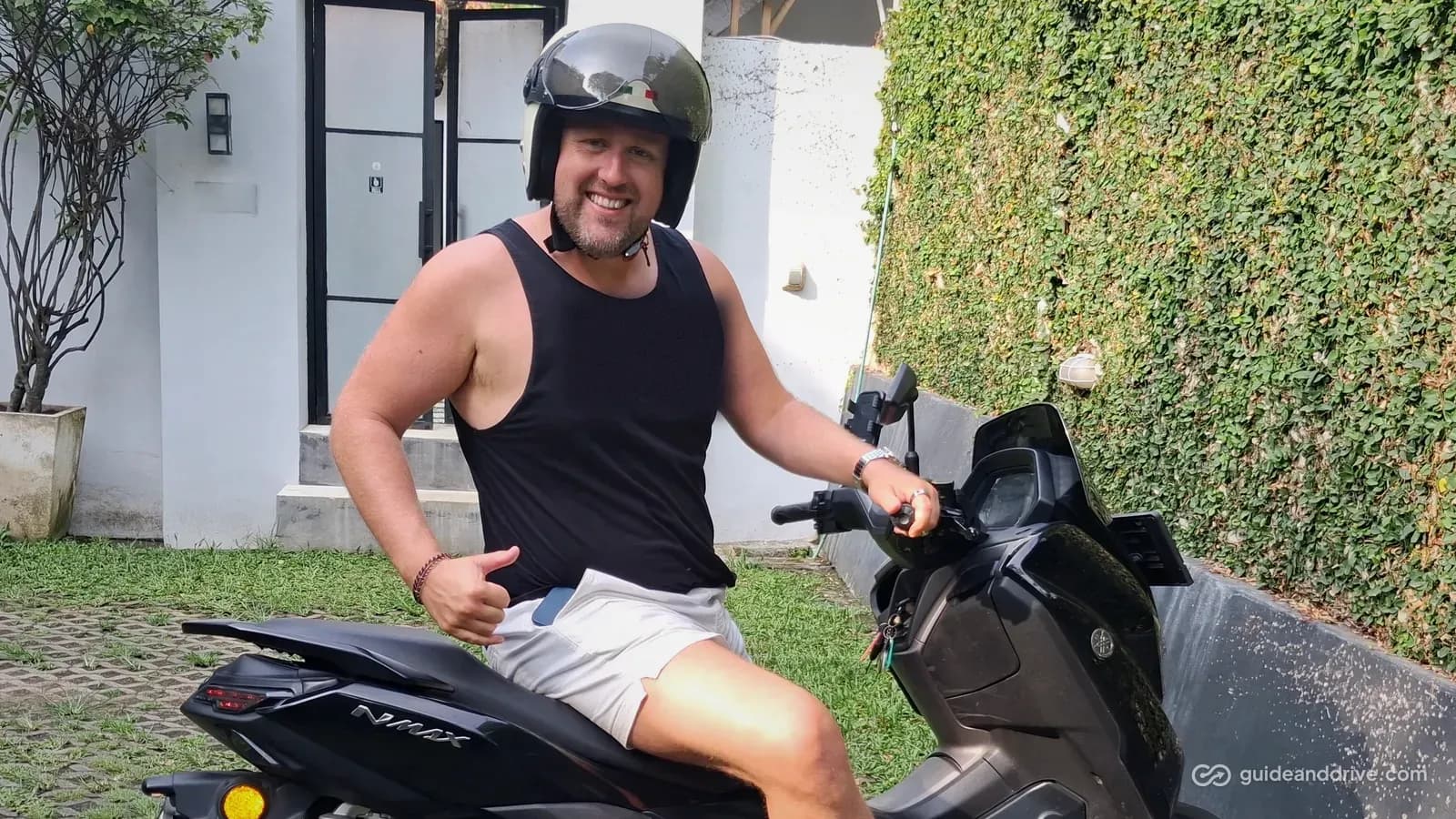 Smiling rider in a helmet on a black Yamaha NMAX scooter